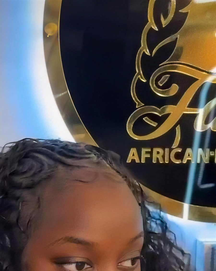 Client with braided style photographed beneath the salon's gold Fatou sign